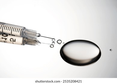 Injection syringe with a drop of drug on a stainless steel background.