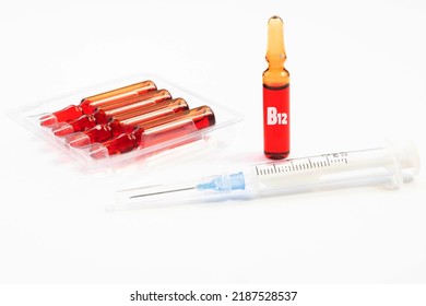 Injection Of Vitamins B 12 On A White Background. Ampoules With Red Liquid. Beauty And Health Concept. Copy Space. Selective Focus