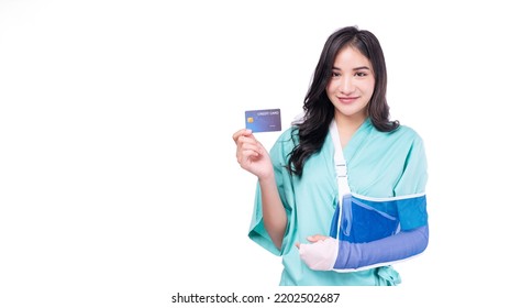 Injured Asian Woman Patient Accident Broken Hand Soft Splint Arm Showing Mock Up Credit Card Standing On White Background. Smile Young Girl Hold Empty Card Over Isolated.Insurance Accident Health Care