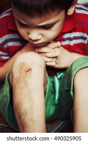 Injured Boy Looks At His Scraped Knee 