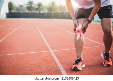 Injured by fitness concept. Man using hands on his knees while working on the street in a park with copy space for text. runner have knee ache due to Runners Knee or Patellofemoral Pain Syndrome.