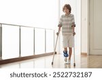 Injured child on crutches. Boy in cast on foot and leg. Little kid with sprained ancle learning to walk again. Physiotherapy in health clinic. Orthopedic trauma treatment. Doctor helping young patient