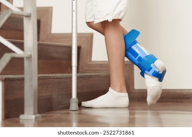 Injured child on crutches. Boy in cast on foot and leg. Little kid with sprained ancle learning to walk again. Physiotherapy in health clinic. Orthopedic trauma treatment. Doctor helping young patient - Powered by Shutterstock