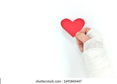 Injured Hands Holding Red Heart In White Background. Selfless Love, Sacrifice And Genuine Kindness Concept.