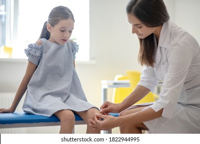 Injured Knee. Doctor Applying Plaster On The Girls Knee