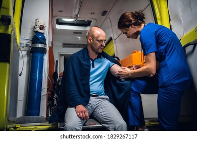 Injured Man In A Blanket Is Getting First Aid In An Ambulance Car.