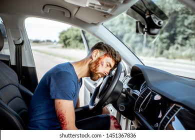 Injured Man With A Broken Head And Bleeding Wounds Sitting On The Driver Seat Without Consciousness After The Road Accident Inside The Car