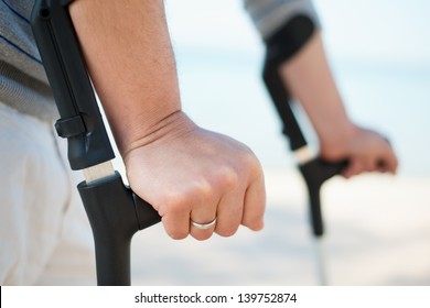 Injured Man Trying to walk on Crutches at a beach - Powered by Shutterstock