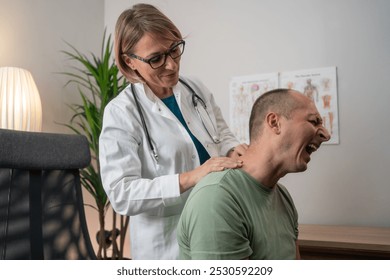 Injured mature man touching neck near doctor in consultation room. Healthcare consultation. medicine, healthcare and people concept - male patient showing sore arm to female doctor at medical office - Powered by Shutterstock