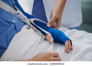 Injured patient showing doctor broken wrist and arm with bandage in hospital office or emergency room. Sprain, stress fracture or repetitive strain injury in hand. Nurse helping customer. First aid. - Shutterstock ID 2288309465