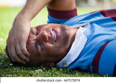Injured rugby player with eyes closed lying on playing field - Powered by Shutterstock