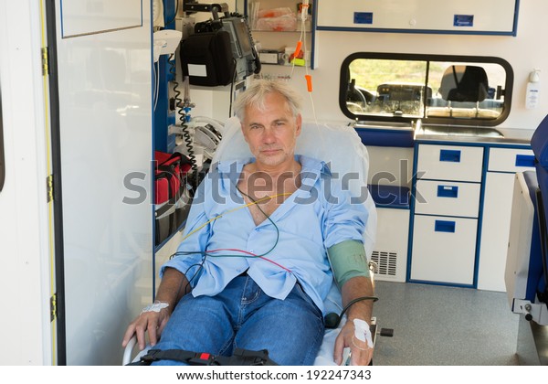 Injured\
senior man sitting on stretcher in ambulance\
car