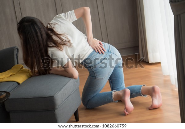 injured woman with lower back spinal pain; portrait
of asian woman breaking her lower back, spine injury, hand holding
back muscle; concept of herniated disc or back pain; 30s adult
asian woman model