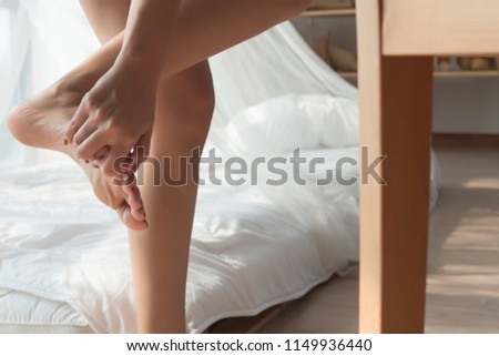 injured woman with pain from injured foot finger; portrait of asian woman kicking a chair with pain at her leg, toe or foot finger; concept of wound, injury, pain from accident; asian woman model