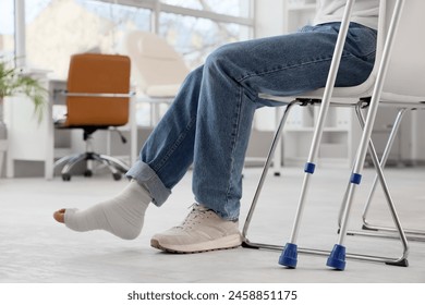 Injured young man after accident with crutches sitting in clinic - Powered by Shutterstock