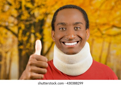 Injured young positive black hispanic male wearing neck brace and smiling to camera giving thumb up, yellow abstract background - Powered by Shutterstock