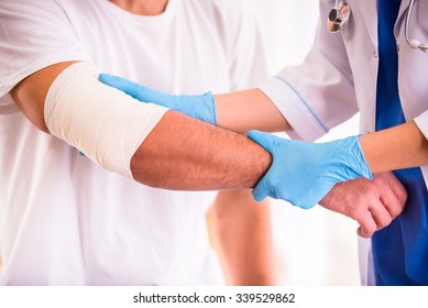 Injury hands. Young man with injured hands. Young woman doctor helps the patient