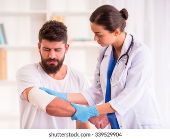 Injury hands. Young man with injured hands. Young woman doctor helps the patient - Powered by Shutterstock