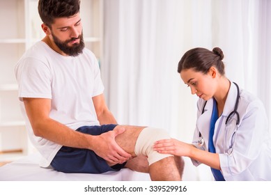 Injury Leg. Young Man With Injured Leg. Young Woman Doctor Helps The Patient