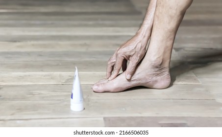 Injury or pain in the foot of an elderly man on a wooden floor