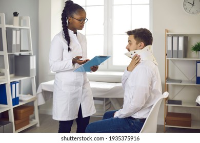 Injury treatment after accidents. Worried man wearing neck collar consulting doctor and asking for help. African physiotherapist or traumatologist at clinic listening to Caucasian patient's concerns - Powered by Shutterstock