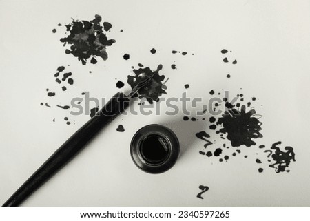 Ink blots, pen and ink bottle on white background, top view