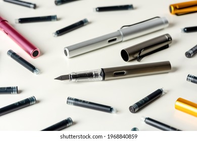 Ink pens and ink cartridges are scattered on the table.