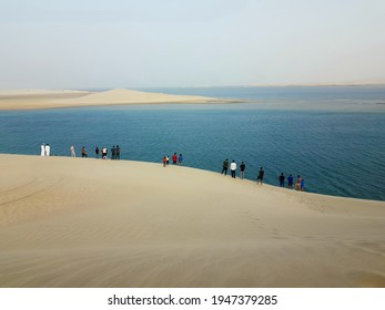 Inland Sea, Qatar, February 2021: People Enjoying View Of Sand Dunes Meeting The Sea, A Specialty Of Qatar. People Enjoy Spending Time In Sand Dunes, Dune Bashing Even During Sand Storm Days.