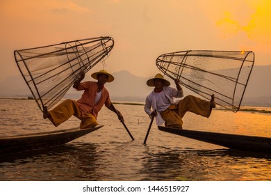 Inle Lake, Myanmar »; Spring Of 2018: Two Traditional Fishermen From Lake Inle Lake, One In White And The Other In Orange Lifting The Net Down And Holding It With Their Feet