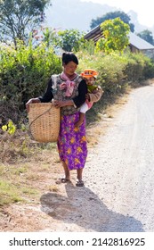 Inle Lake, Shan State, Myanmar, January 23, 2017 - Backlit Burmese Woman Carrying Cute Shy Toddler On Her Back While Holding A Large Basket