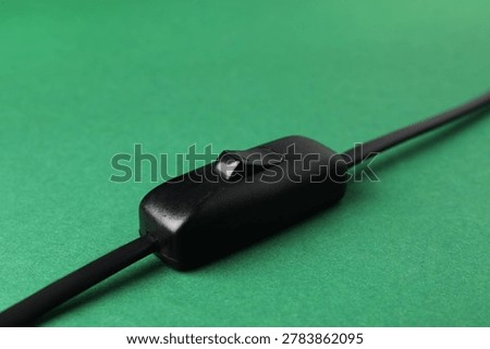 Inline cord switch for lamp on green background, closeup