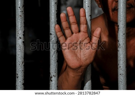 Inmate Hands Behind Bars Representing Incarceration, Black Background