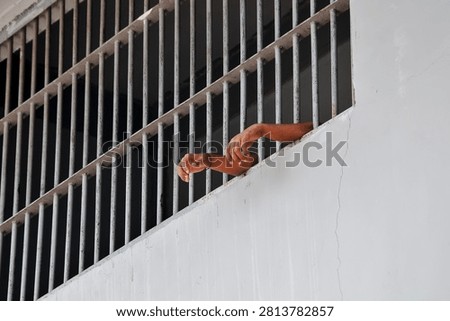 Inmate Hands Behind Bars Representing Incarceration, Black Background