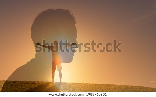Inner happiness, feeling\
inspired, and positive thinking concept. Young man silhouette\
outdoors with arms up to the sunlight sky feeling enlightened and\
energized. \
