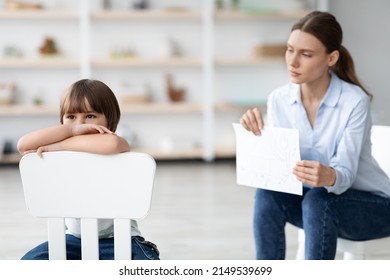 Inner Mental Problems. Stressed Little Boy Sitting On Chair And Feeling Upset, Ignoring Professional Woman Psychotherapist With Picture During Therapy, Free Space