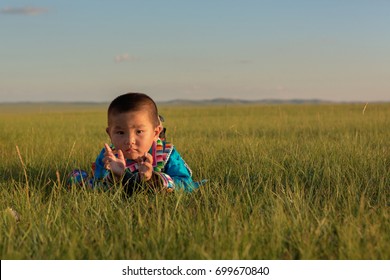 Inner Mongolia, China-July 30, 2017: Nomadic Mongolian Child With His Traditional Colorful Dresses Near Their Yurt In Immense Grassland Of The Country.