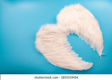 Innocence And Purity, Christian Mythology And Innocent Celestial Creatures Concept With Guardian Angel Wings Made Of White Feathers Isolated On Blue Background With Copy Space