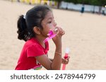 Innocence and wonder collide as a young explorer conjures bubbles by the shore