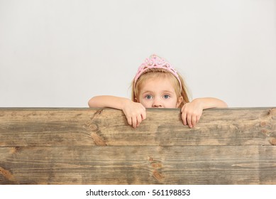 Innocent child peeking over wood border