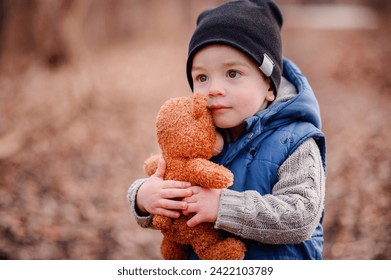 Innocent toddler clutching a teddy bear, a comforting presence on his outdoor adventure