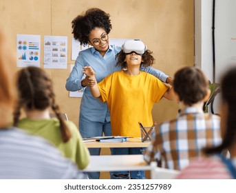 Innovation in education. Student schoolgirl  in virtual reality glasses together with teacher during lesson in bright classroom at school
