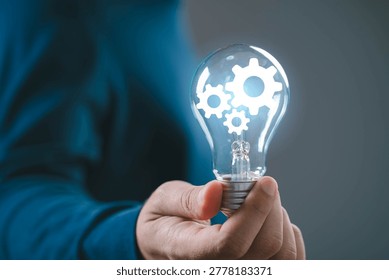 Innovation process concept with light bulb and gear mechanism, hand holding idea symbolizing problem solving, business development, creative thinking, engineering solution and smart system integration