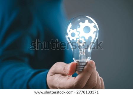 Innovation process concept with light bulb and gear mechanism, hand holding idea symbolizing problem solving, business development, creative thinking, engineering solution and smart system integration