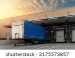 Innovative modern logistics warehouse center complex building exterior bay gate semi-trailer unloading goods distribuition warm blue sunset sky background. Cargo storage facility industry building