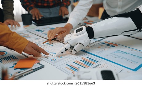 Innovative scene of human and robotic hands collaborating over data reports in a modern workspace, depicting teamwork and creative problem-solving in business analysis.Noogenesis