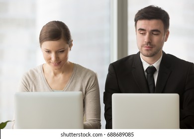 Inquisitive curious businessman with bad manners sneakly looking at laptop screen of businesswoman trying to steal idea of competitor, copying work at corporate exam, gathering information on rival - Shutterstock ID 688689085