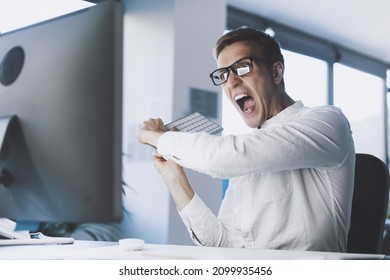 Insane angry businessman having a nervous breakdown, he lost his patience and he is hitting the computer with the keyboard