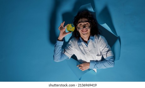 Insane Funny Scientist Studying Petri Dish With Liquid Substance, Doing Crazy Goofy Facial Expressions. Mad Silly Chemist Grinning, Feeling Foolish And Amusing With Wacky Messy Hair.