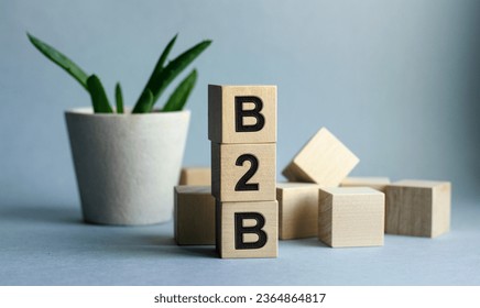 The inscription B2B on wooden cubes isolated on a blue background, the concept of business and finance. - Shutterstock ID 2364864817