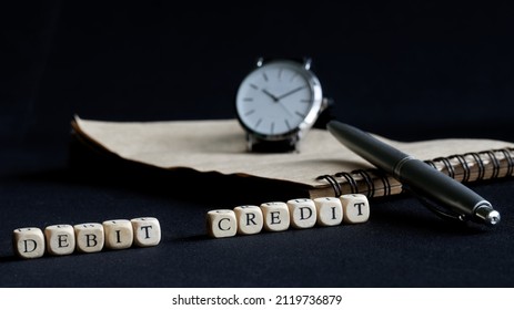 Inscription: Debit Credit On Dark Surface Next To Pen, Notepad And Wristwatch. The Concept Of Timely Accounting Reporting. The Concept Of Fast Financial Decision Making. Selective Focus. Close-up